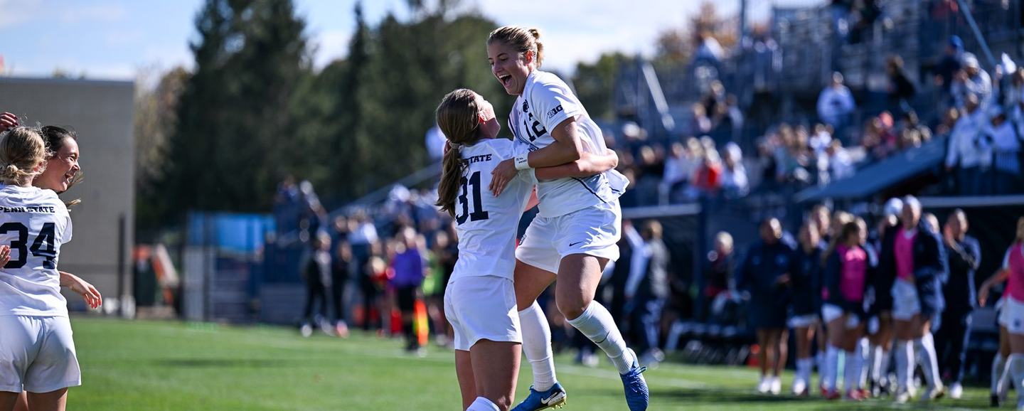 Two Penn State players celebrate a goal, one leaping into her teammate's arms