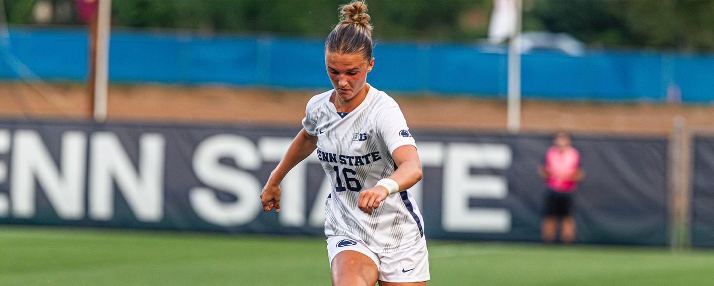 A Penn State player drives forward in front of an oversized Penn State wordmark